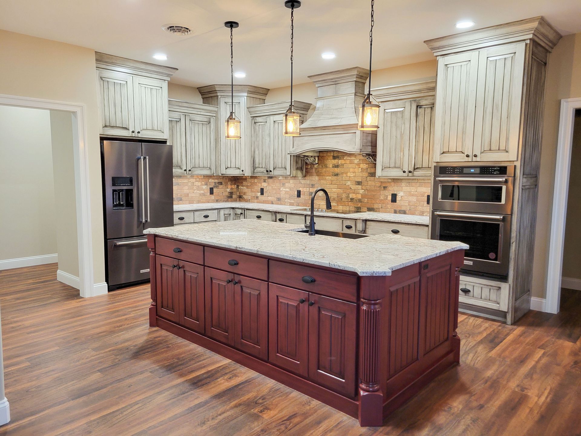 Kitchen with maroon island, beige cabinets, stainless steel appliances, and wood floors.
