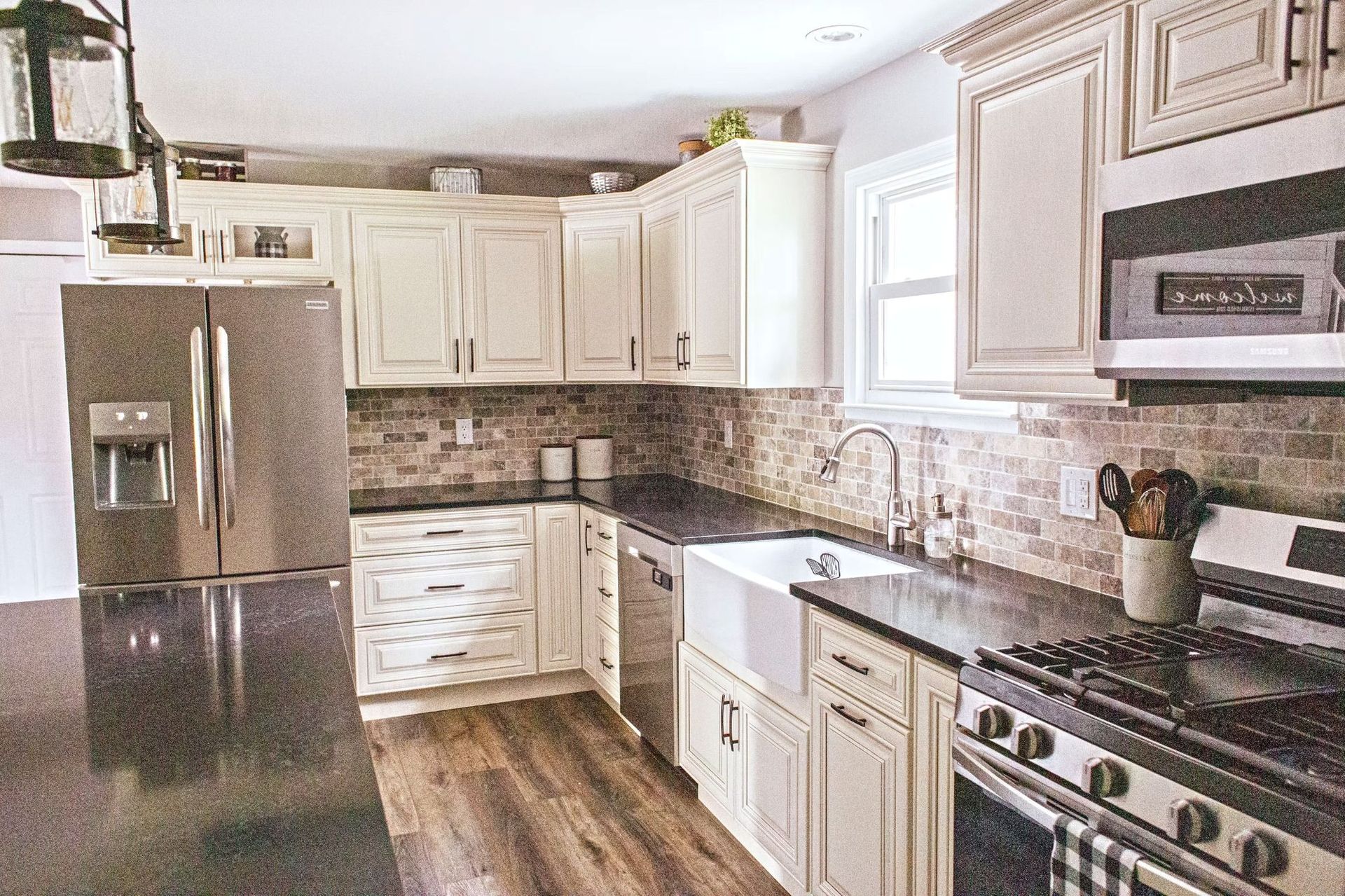 Kitchen with white cabinets, stainless steel appliances, dark countertops, and a farmhouse sink.