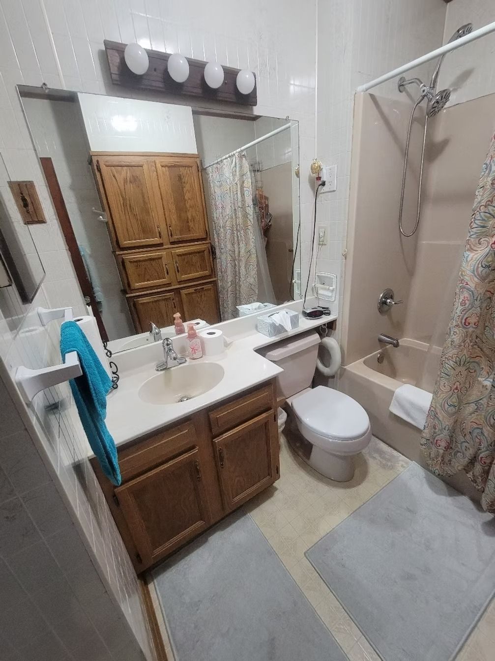 Bathroom with beige walls, wooden cabinets, a pink toilet, and a shower/tub combo.