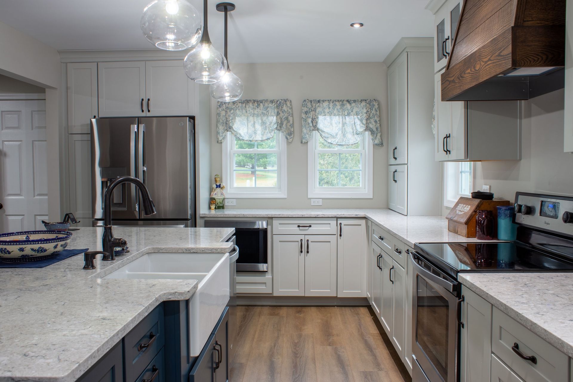 Modern kitchen with white and navy cabinets, stainless steel appliances, and granite countertops.
