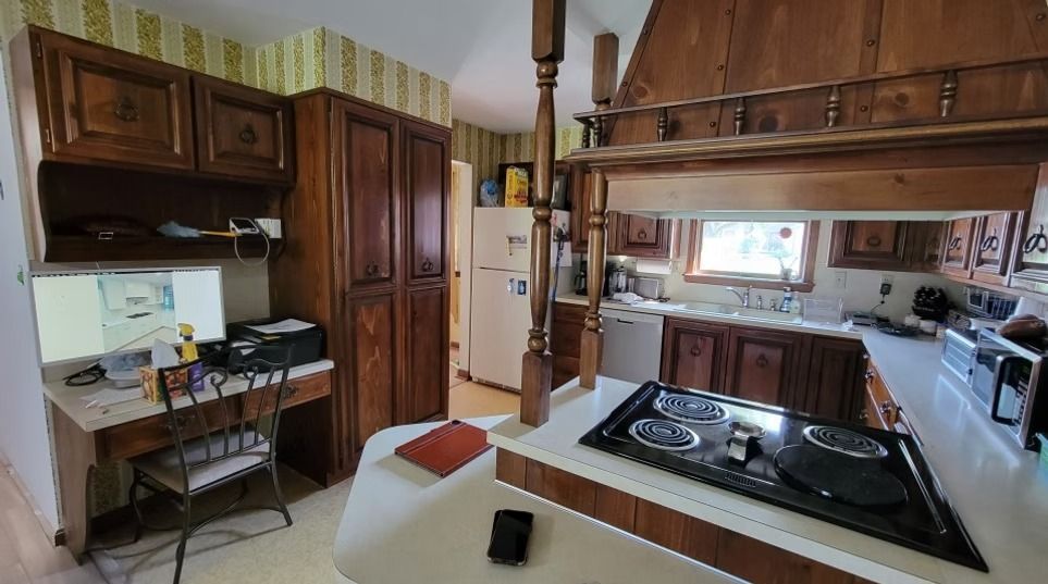 Kitchen with dark wood cabinets, appliances, and an electric stovetop on an island.