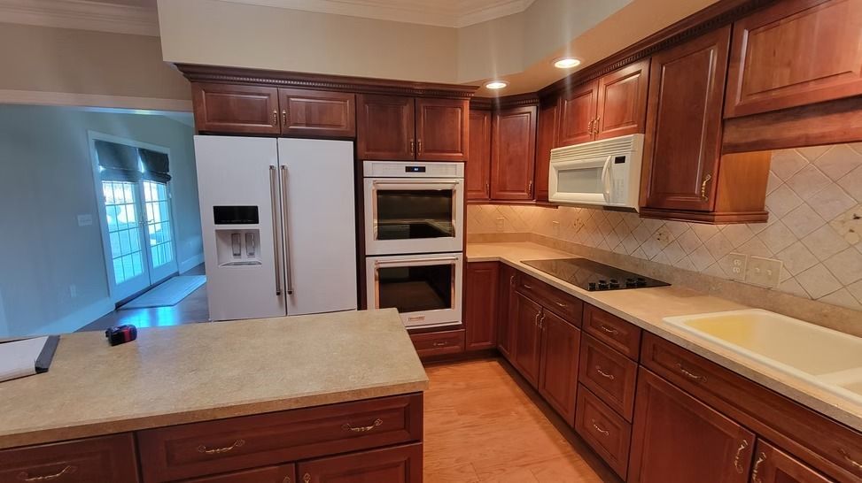 Kitchen with cherry cabinets, white appliances, beige countertops, and a central island.