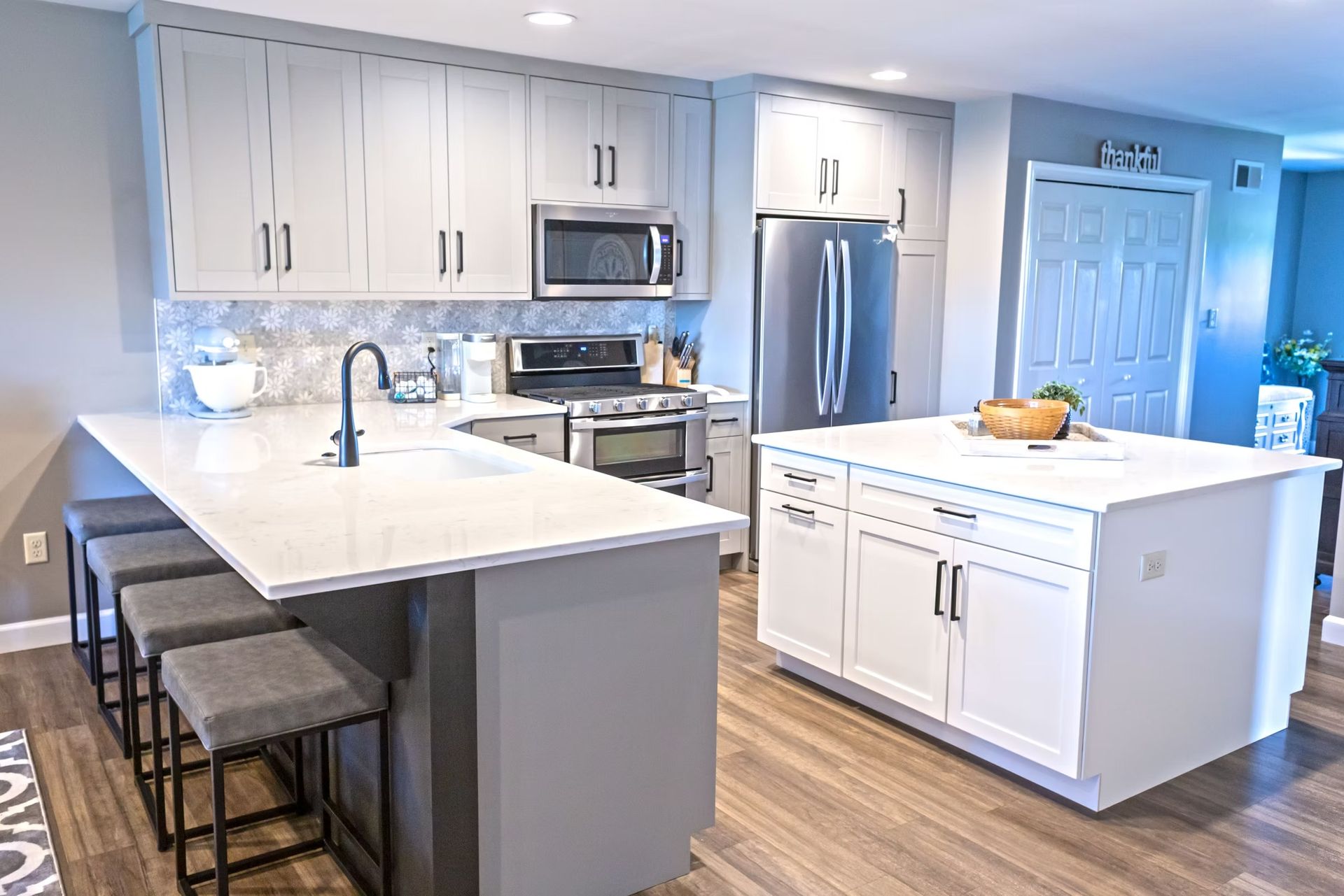 Modern kitchen with gray and white cabinets, countertops, and a kitchen island; bar stools.