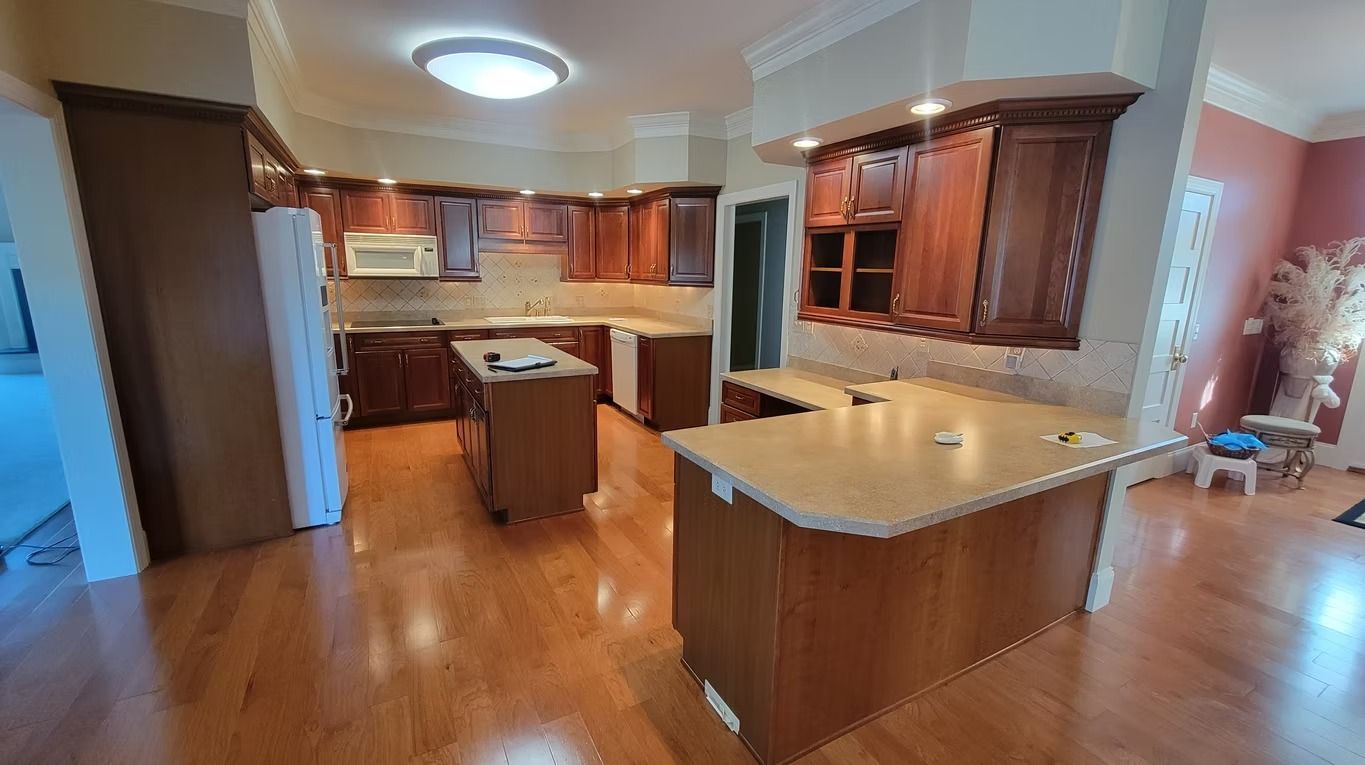 A kitchen with wooden cabinets, two islands, and hardwood floors.