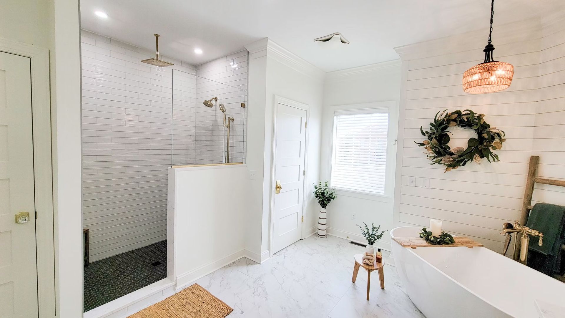 White bathroom with walk-in shower, freestanding tub, and a wood accent wall.