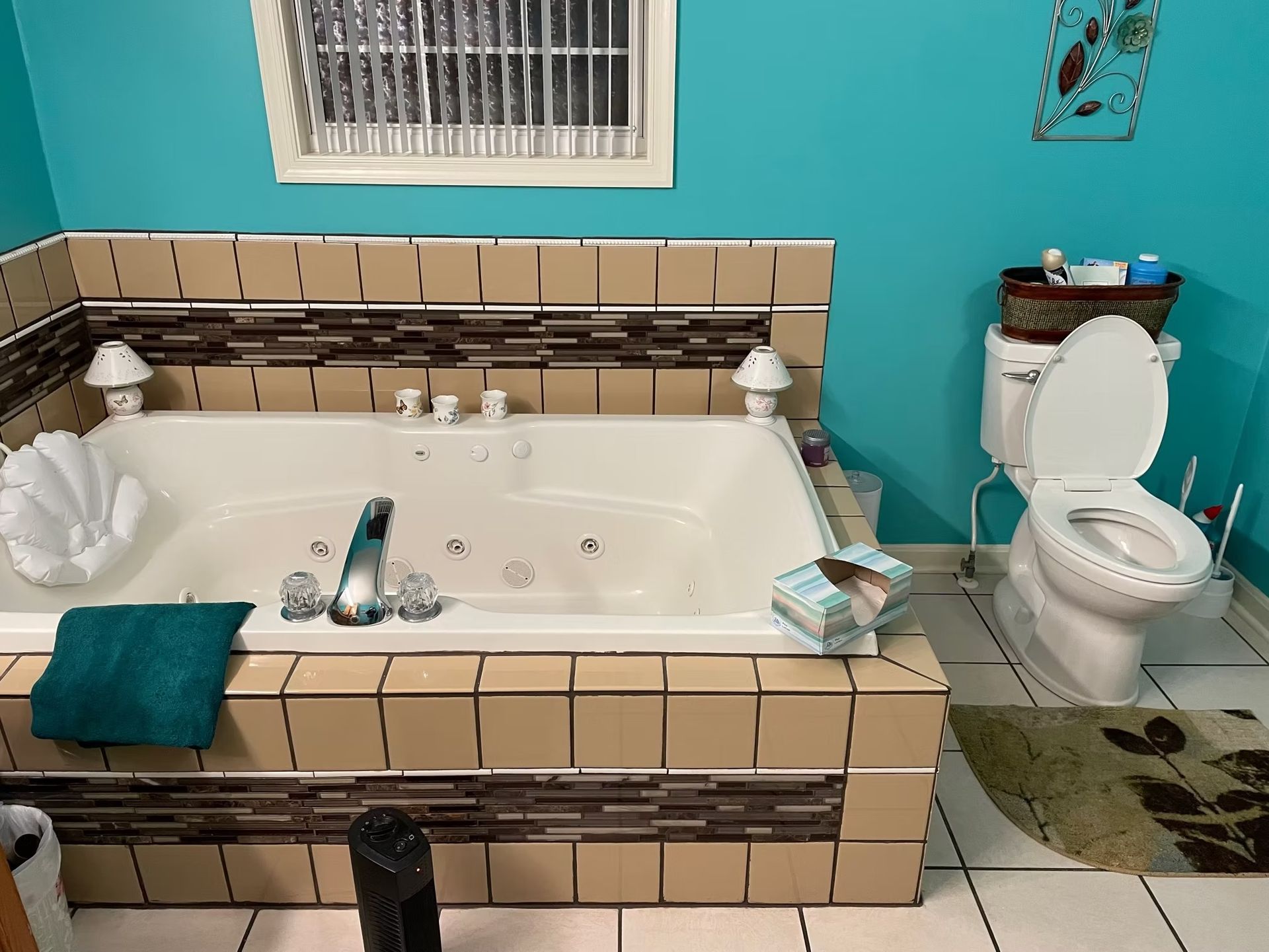 Bathroom with a jacuzzi tub, toilet, and turquoise walls; tan tile surrounds the tub.
