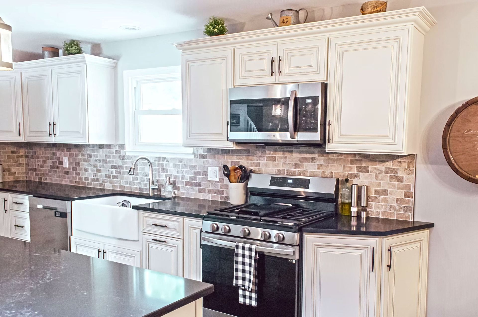 White kitchen with black countertops, stainless steel appliances, and brick backsplash.