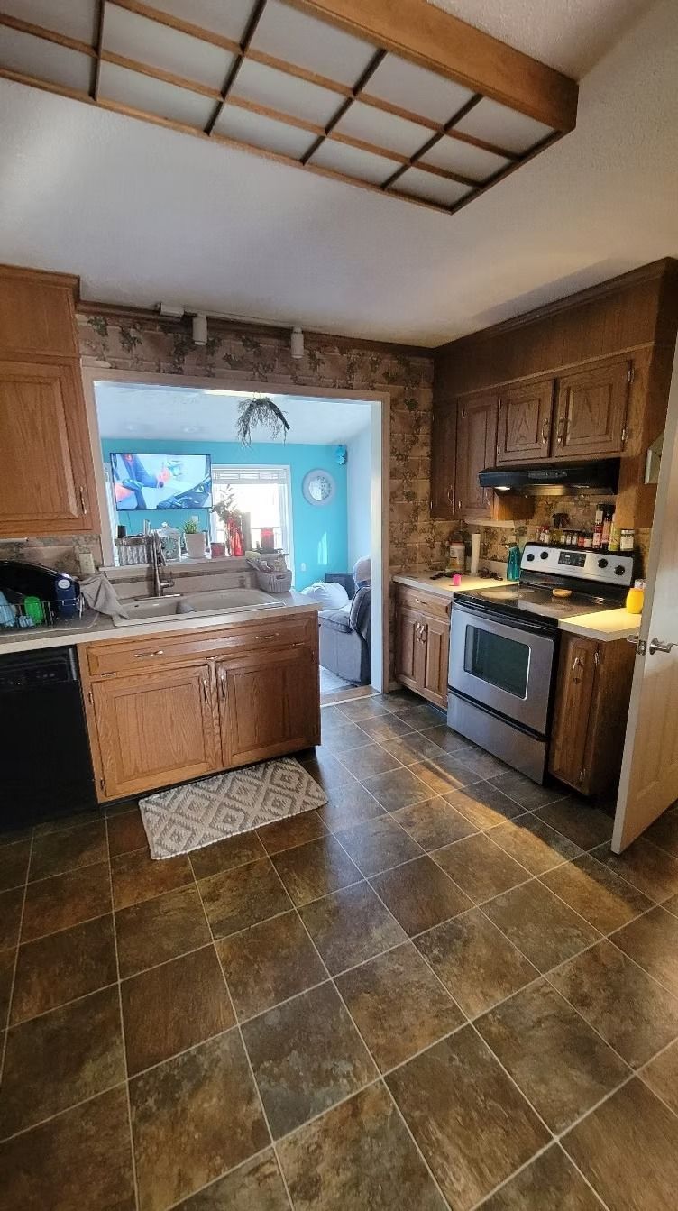 Kitchen with wood cabinets, stainless steel appliances, and brick accent wall.