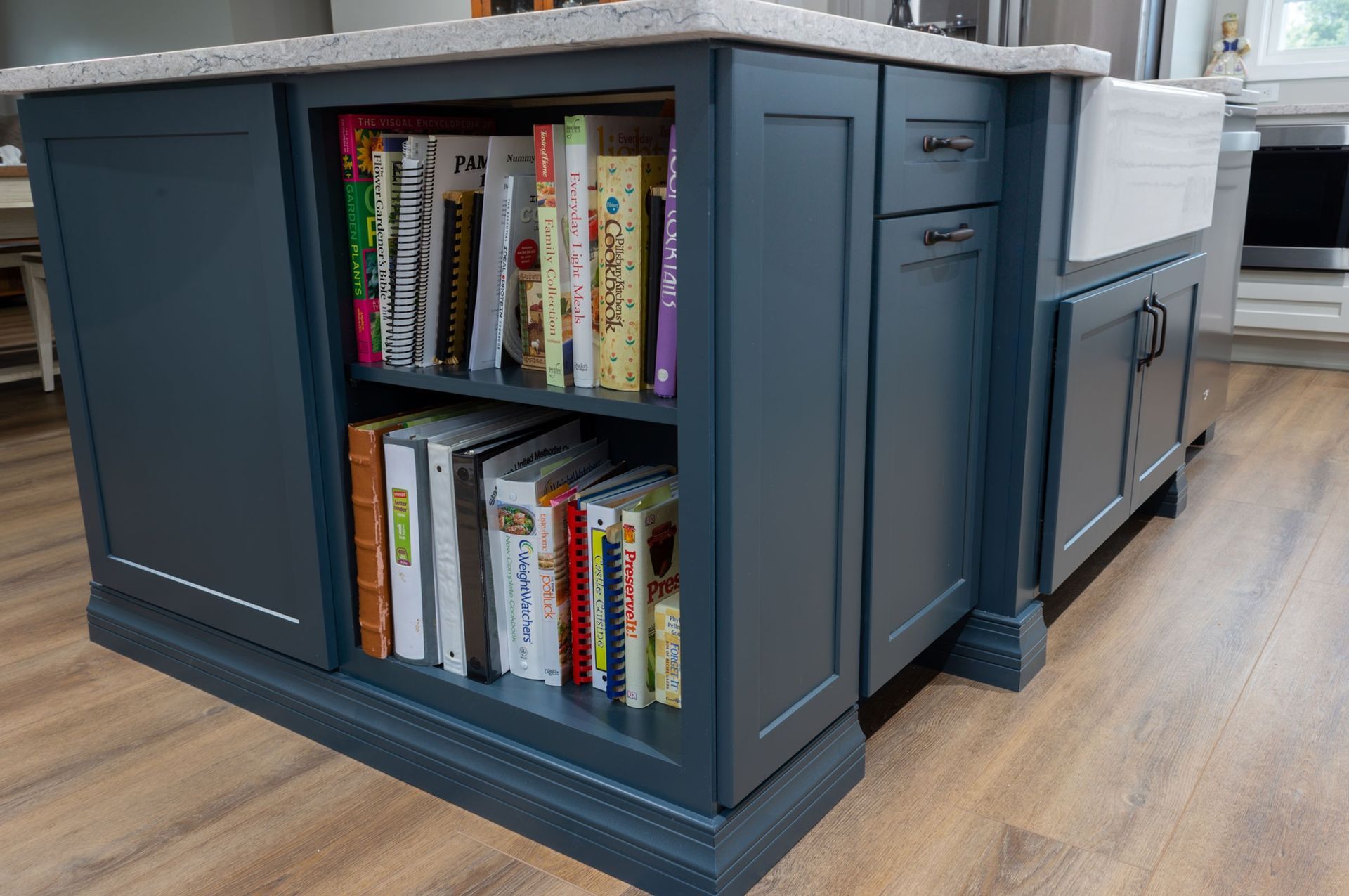 Dark blue kitchen island with open cookbook shelves and cabinet doors.