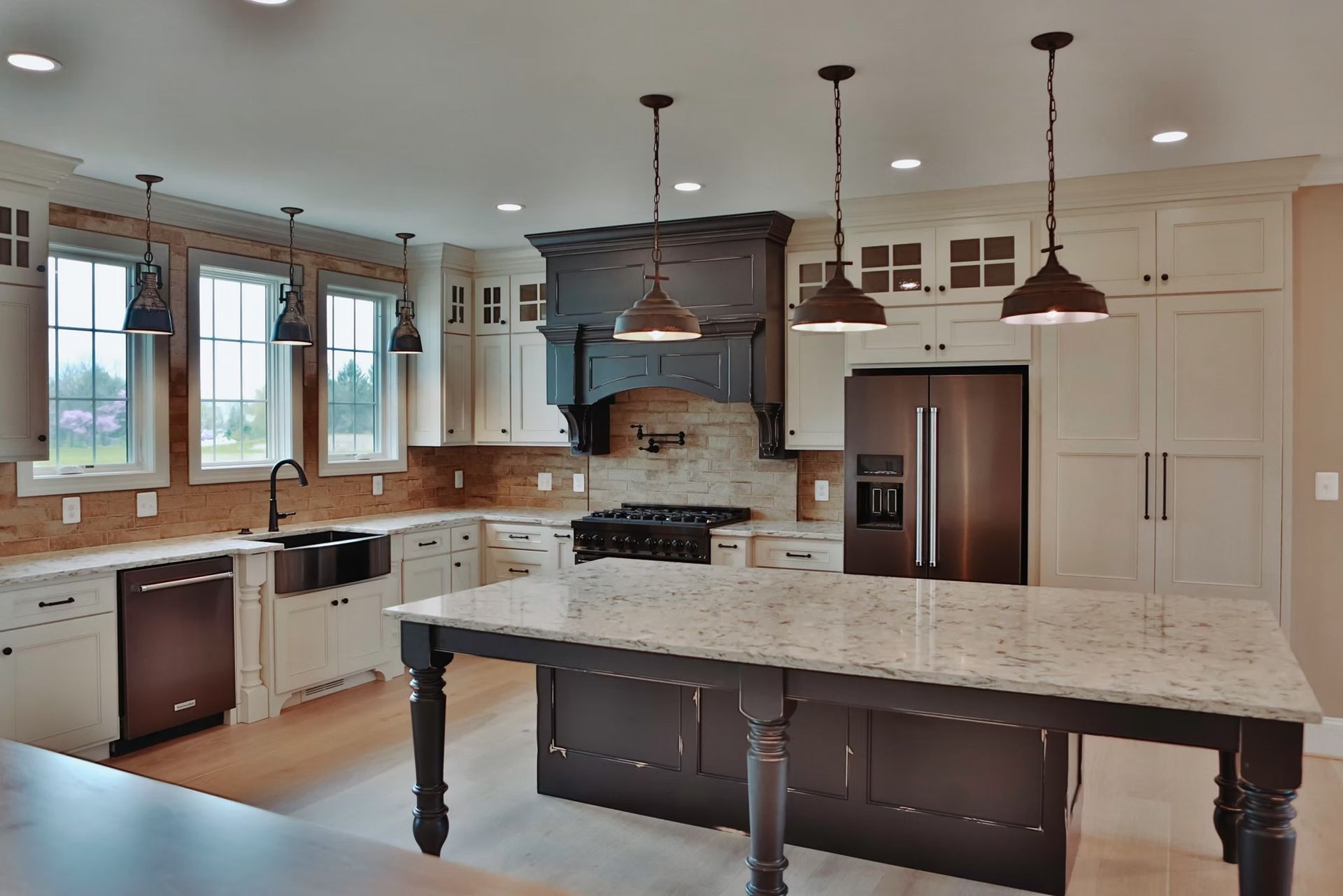 Spacious kitchen with white cabinets, dark island, and stainless steel appliances; windows bring in natural light.