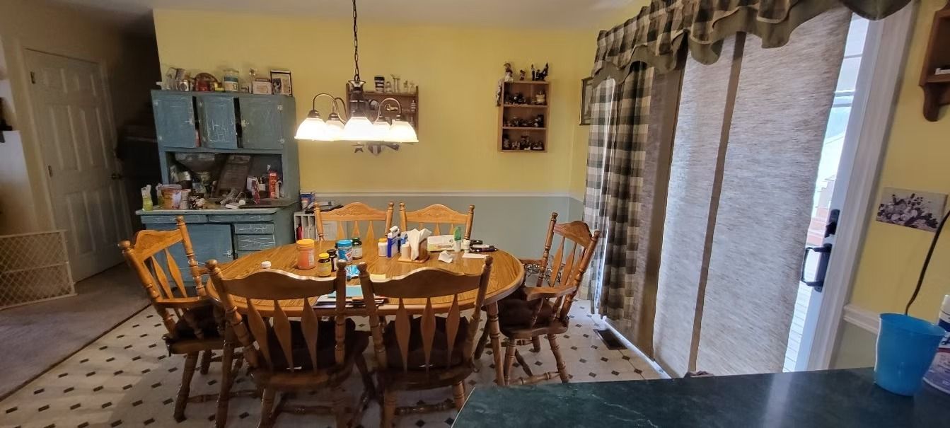 Dining room with wooden table, chairs, and a blue cabinet. Yellow walls and a tiled floor.