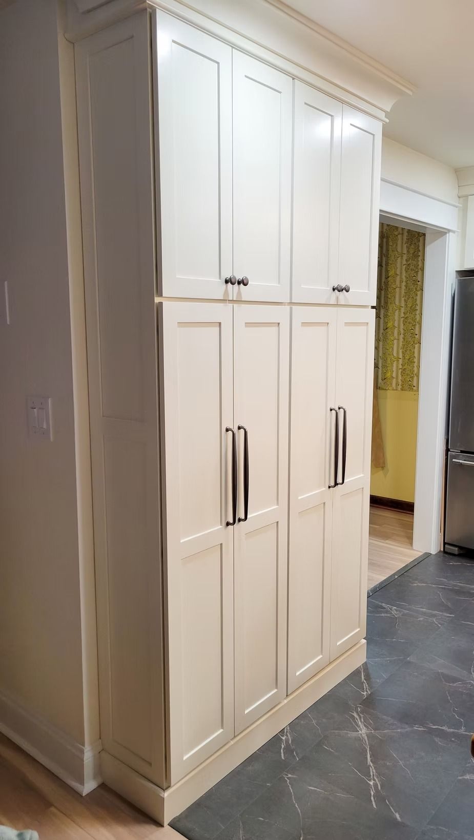 Tall, white kitchen pantry cabinets with black handles.