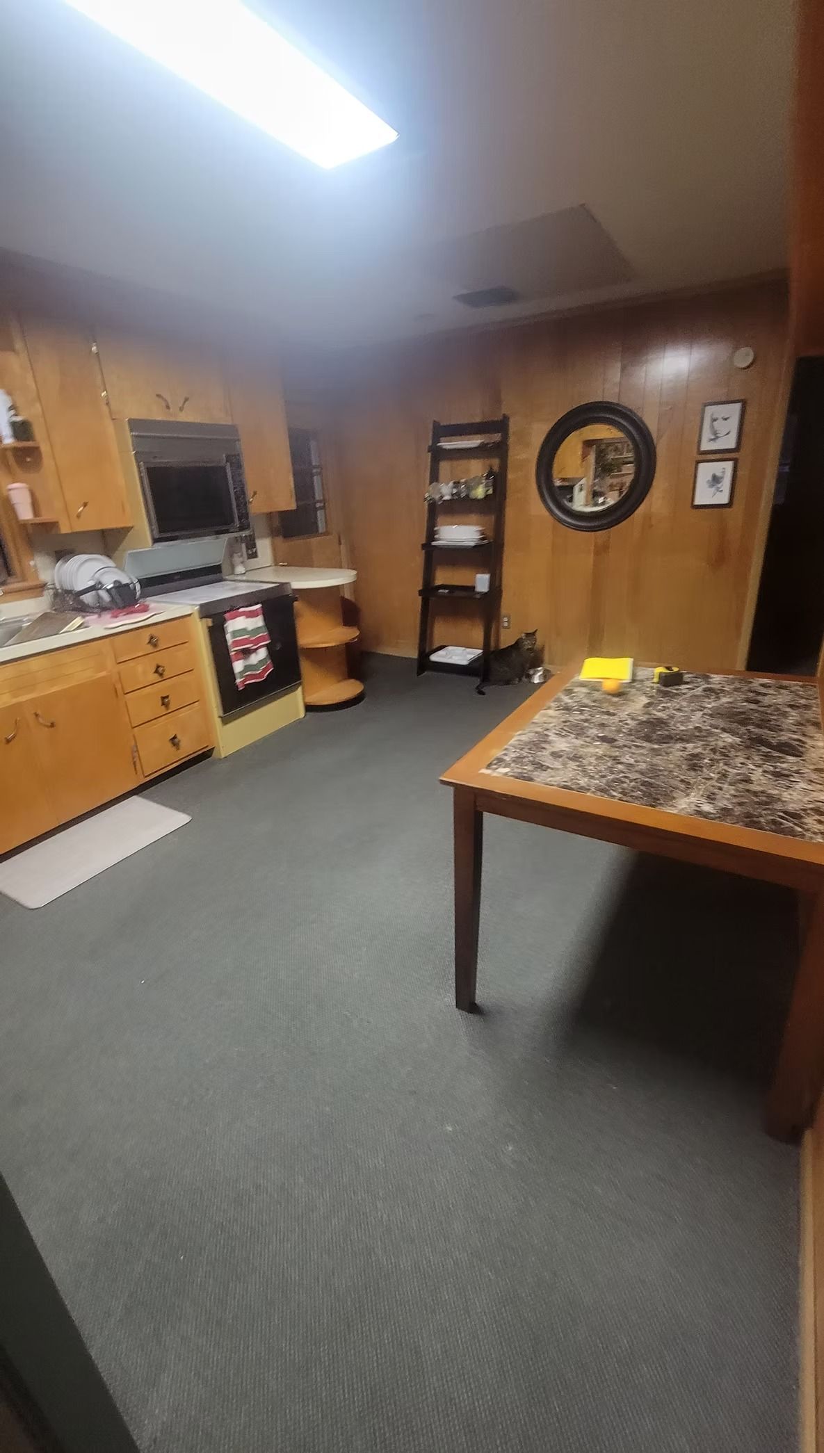 A room with wood-paneled walls, a black carpet, and a table with a patterned top.