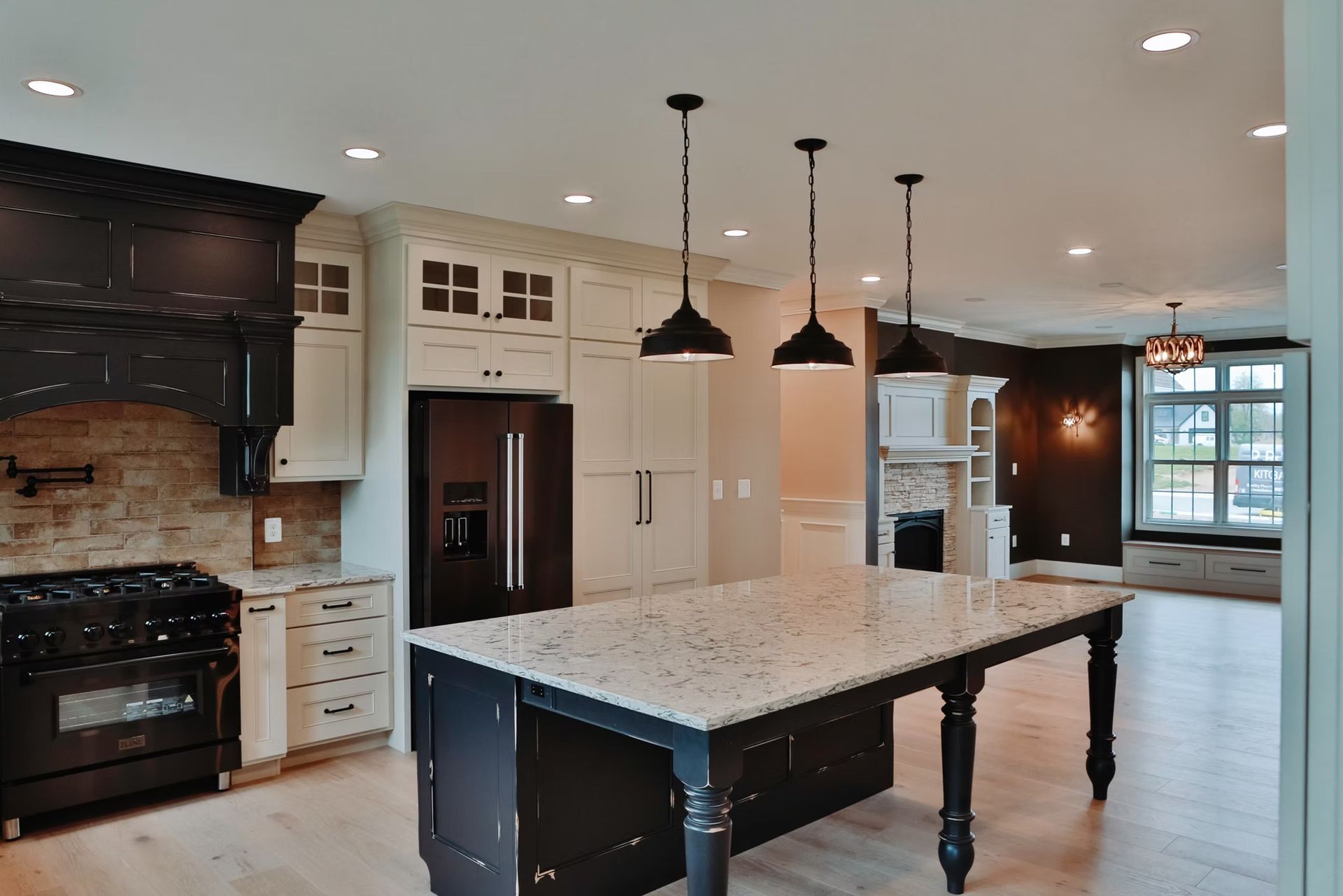 Modern kitchen with a large island, black and white cabinets, and pendant lights.