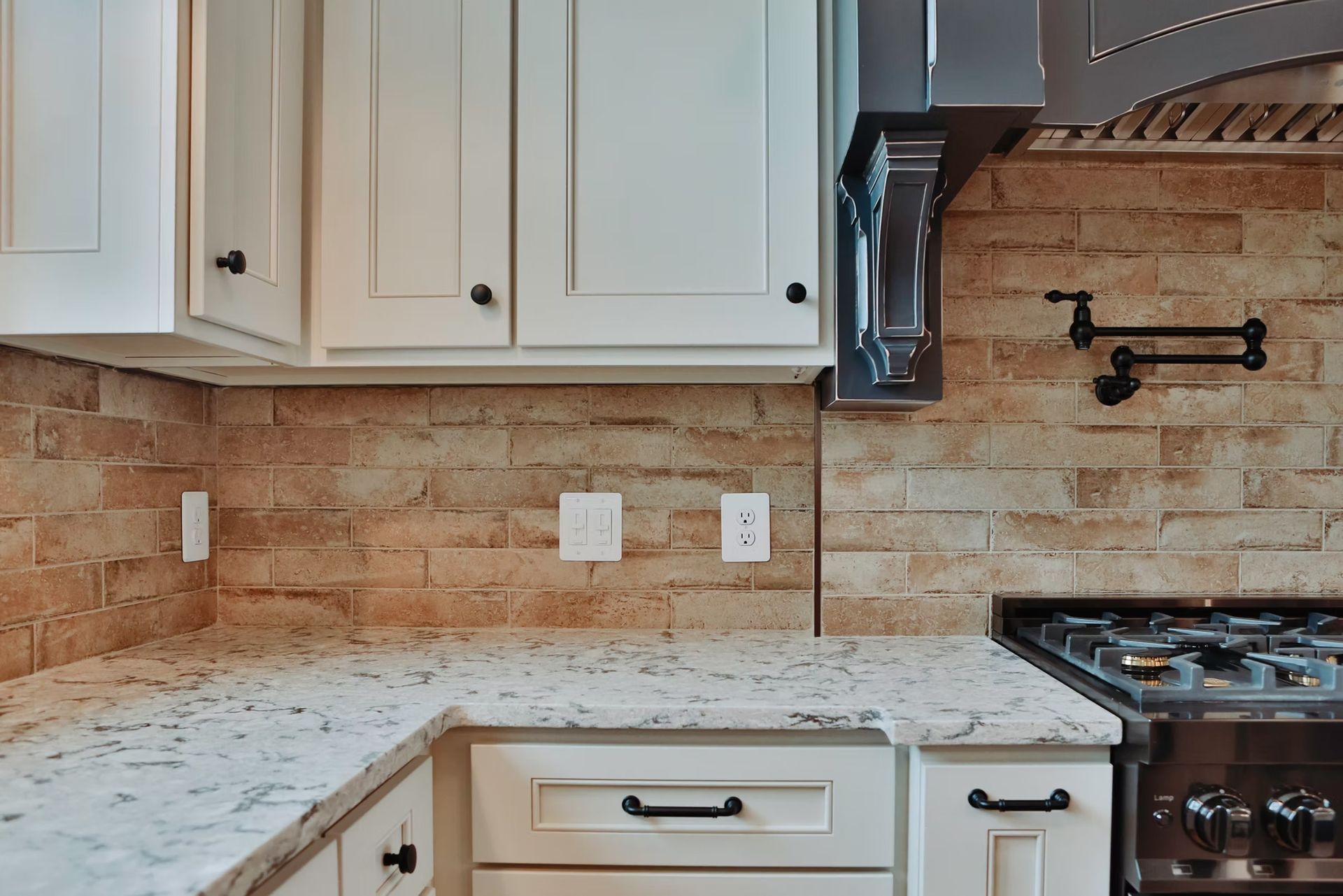 Kitchen with white cabinets, granite countertops, brick backsplash, and gas stove.