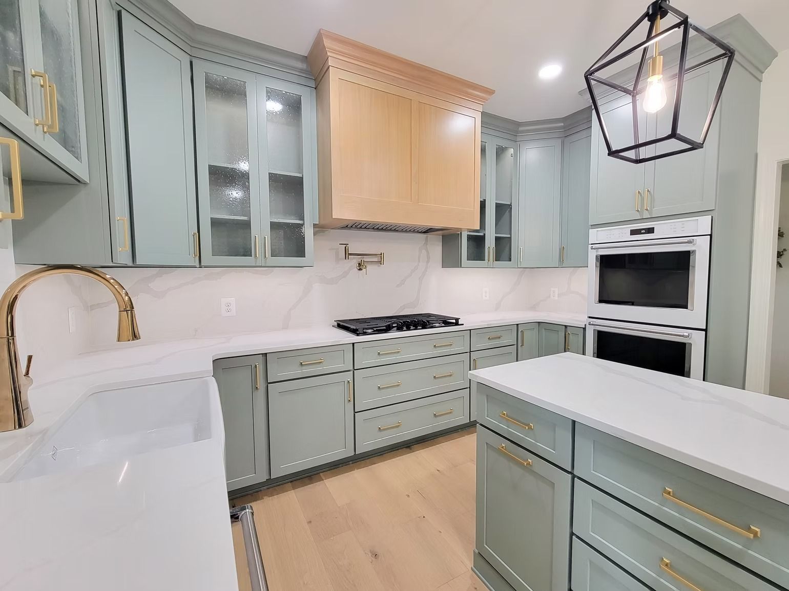 Kitchen with light blue cabinets, white counters, wooden floor, and an island.