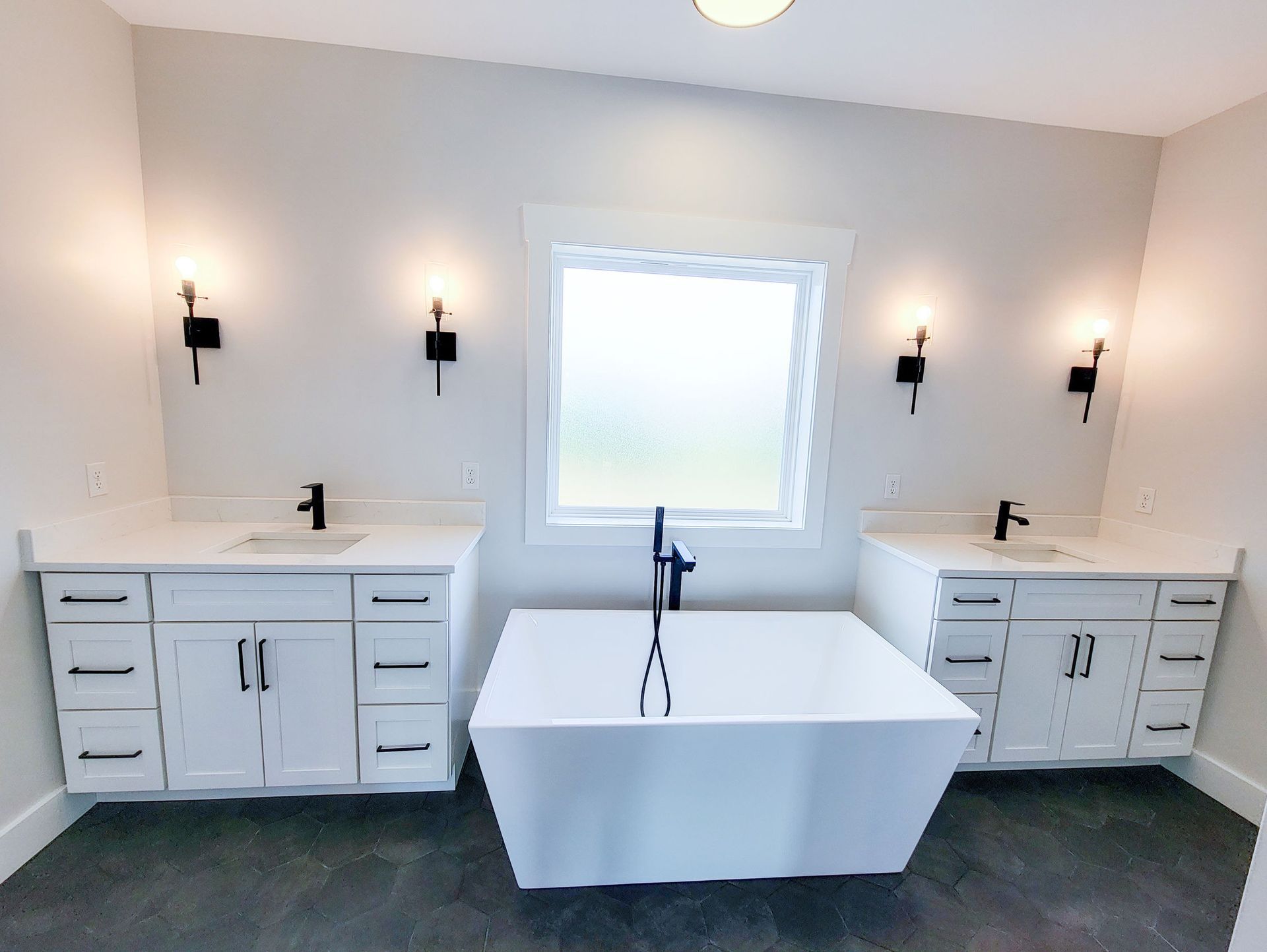 Modern bathroom with white cabinets, a standalone tub, and black fixtures.