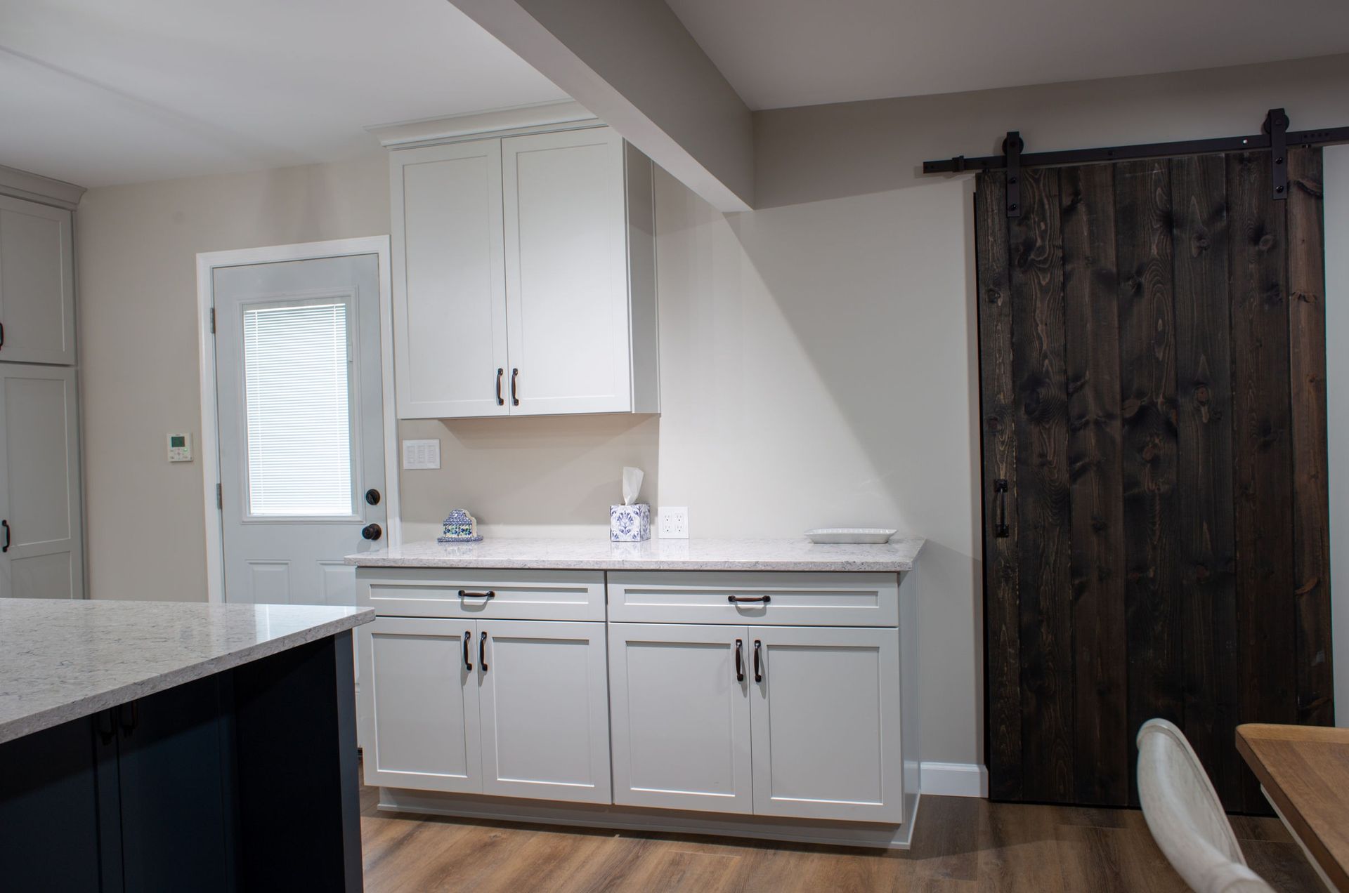 White kitchen cabinets, countertop, wooden sliding door, and a blue island.