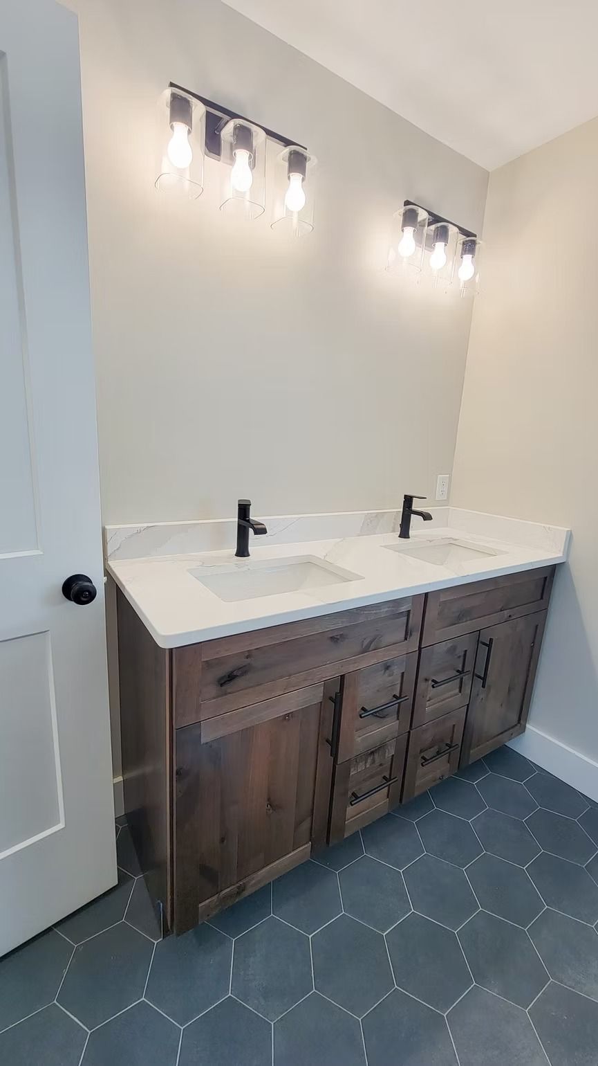 Bathroom with wood vanity, white countertop, black fixtures, and hexagon tile floor.