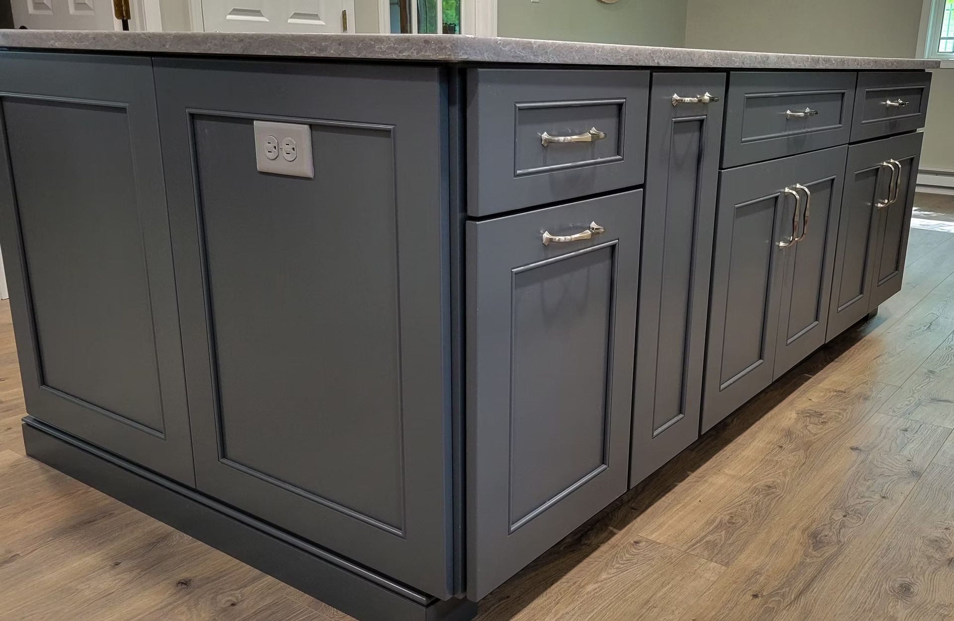 Gray kitchen island with cabinetry, outlet, and hardware.