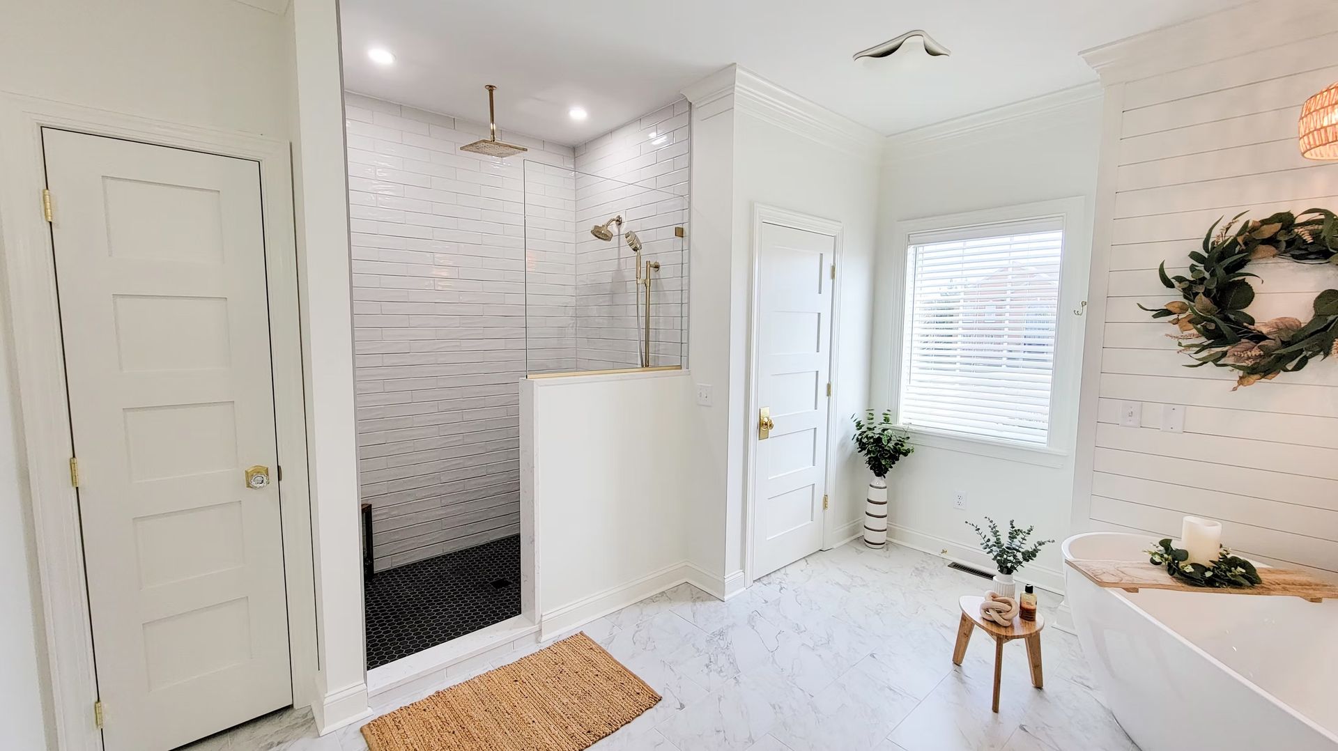 Bright white bathroom with a shower, tub, and window; neutral decor and wood accents.