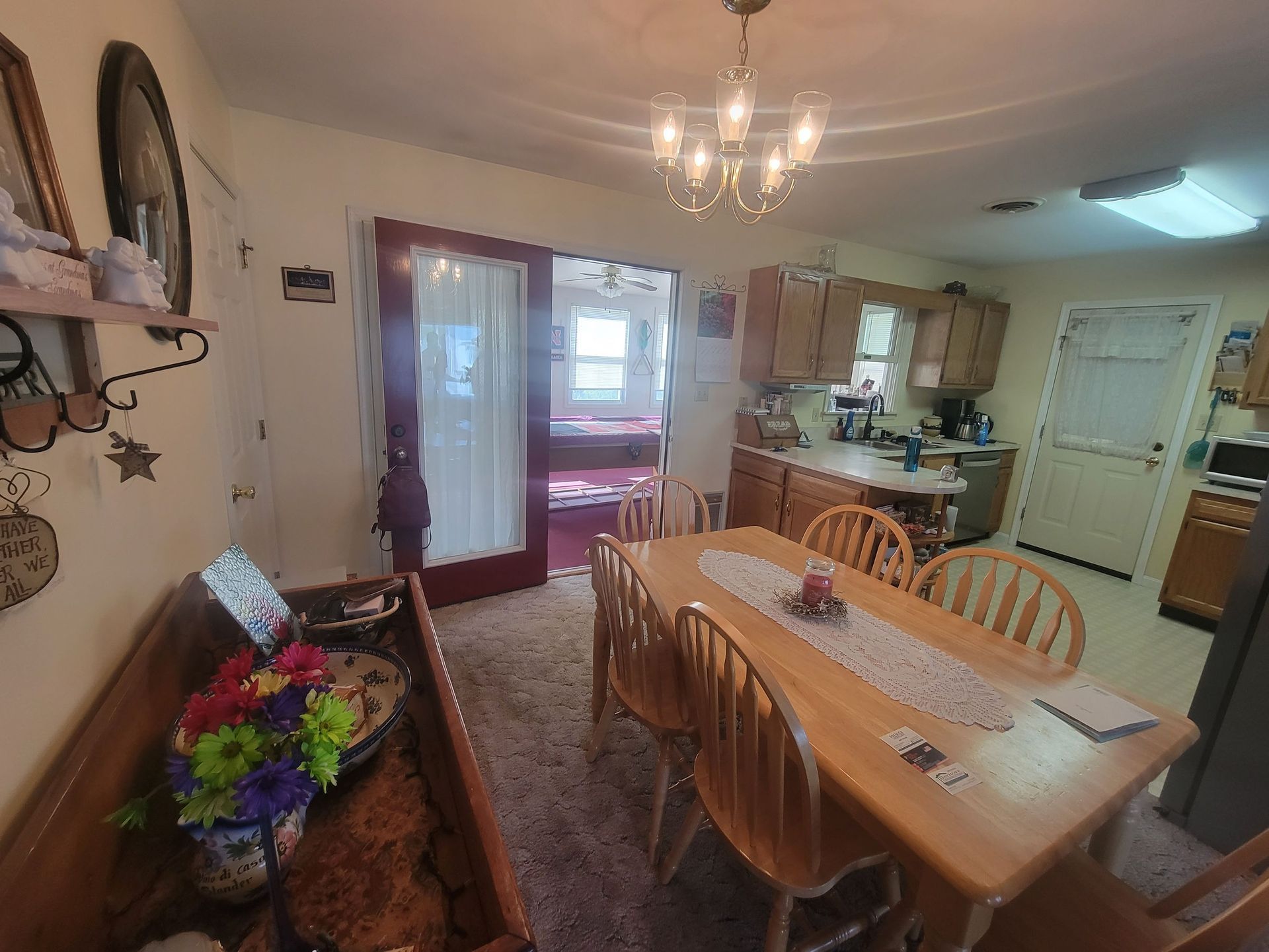 Dining room with wooden table and chairs, opening to a kitchen and bedroom.