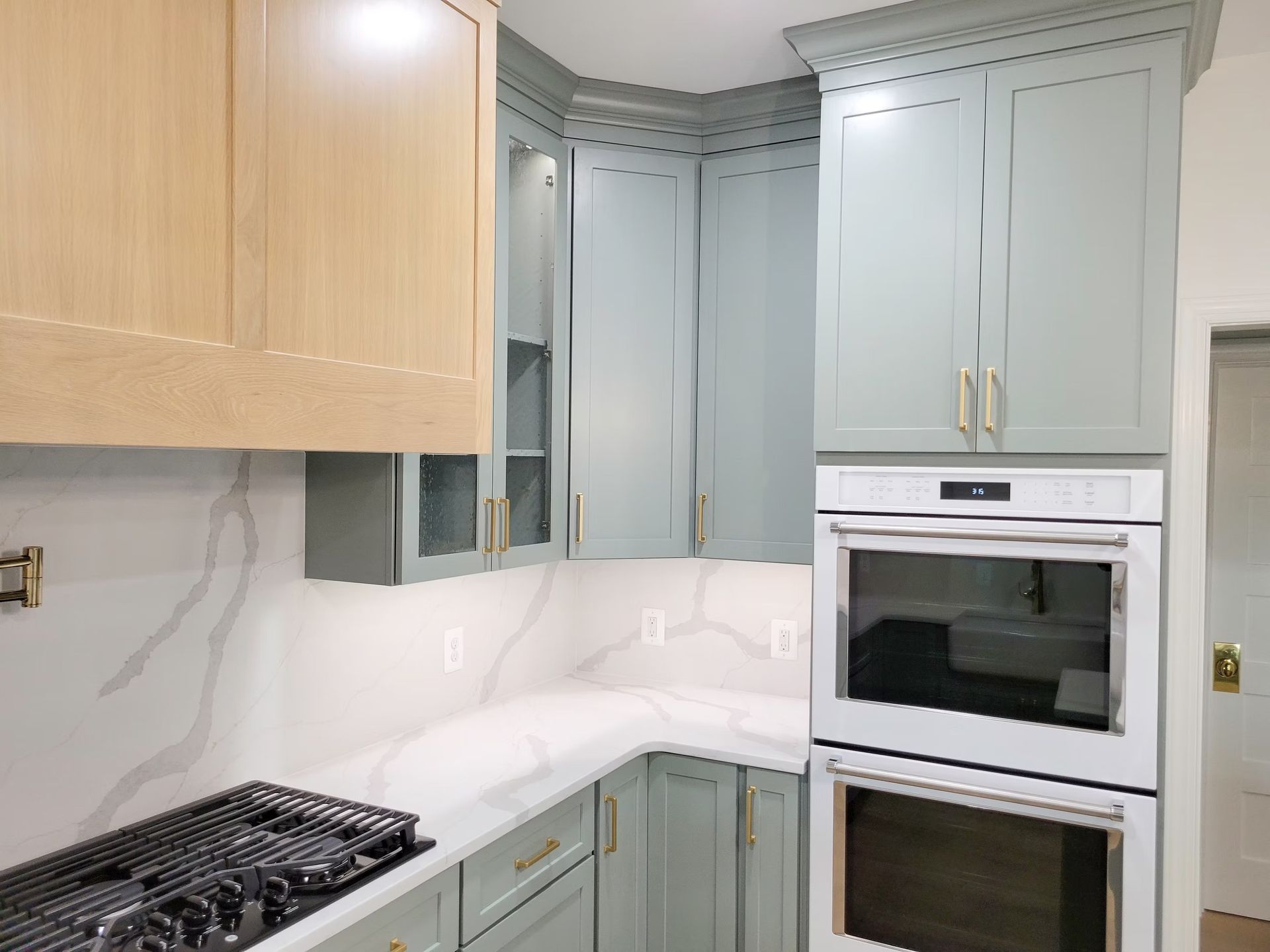 Kitchen with light blue cabinets, white countertops, and a built-in white oven.