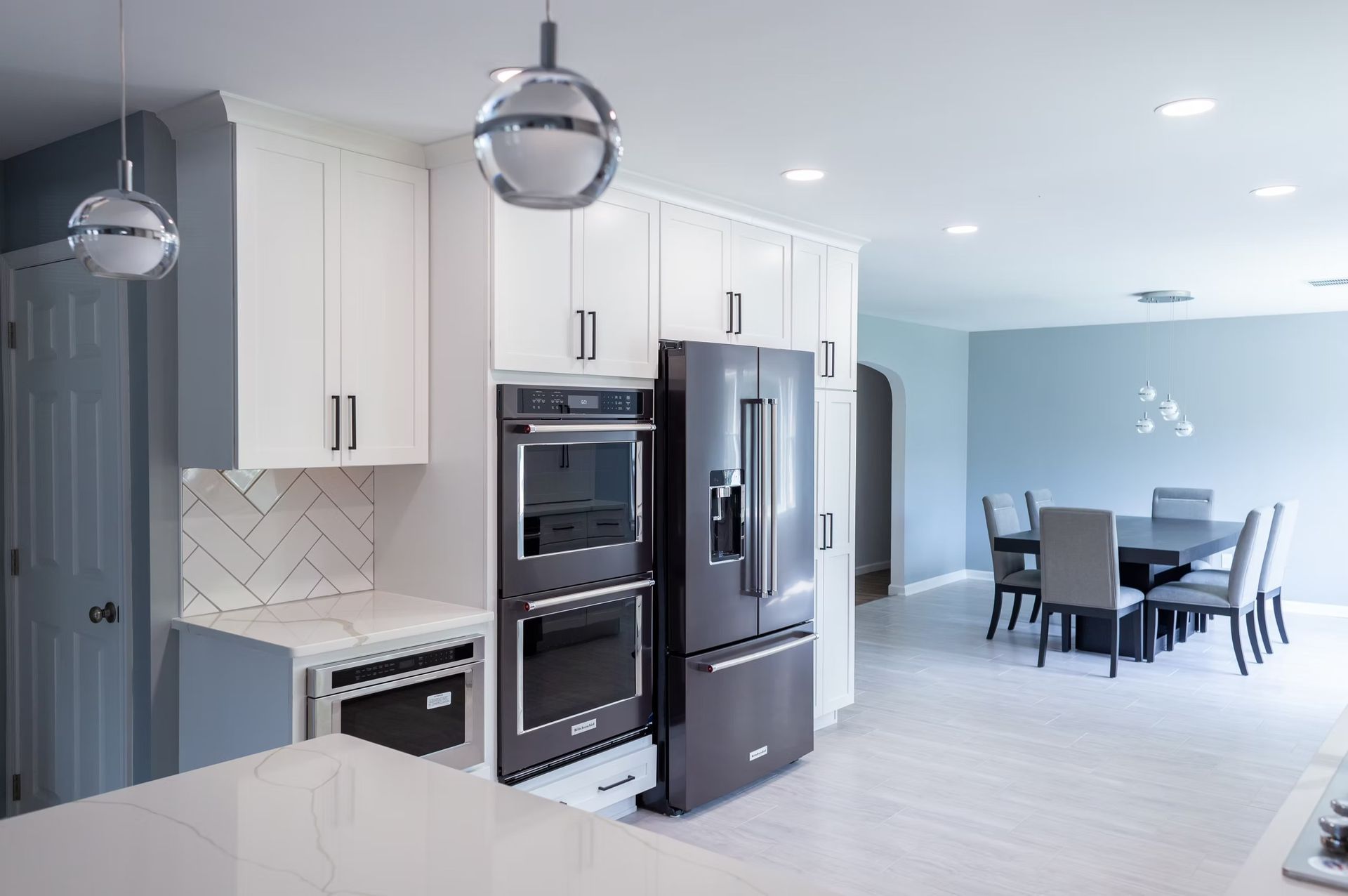 Modern white kitchen with stainless steel appliances and a dining area.