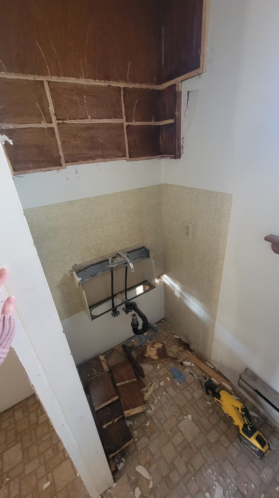 Bathroom renovation in progress; exposed wall, sink plumbing, debris on the floor.