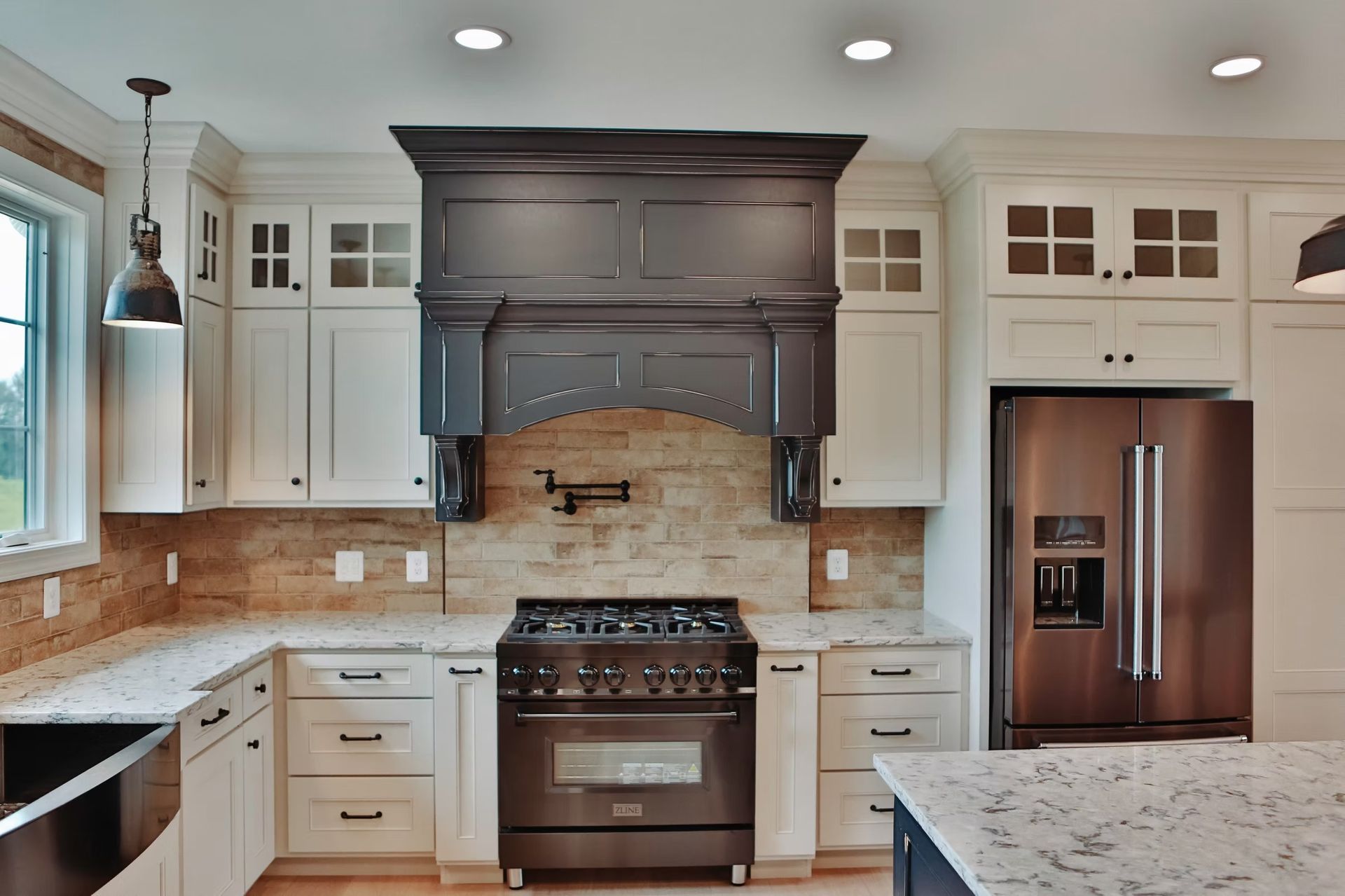 Kitchen with white cabinets, dark range hood, and stainless steel appliances.