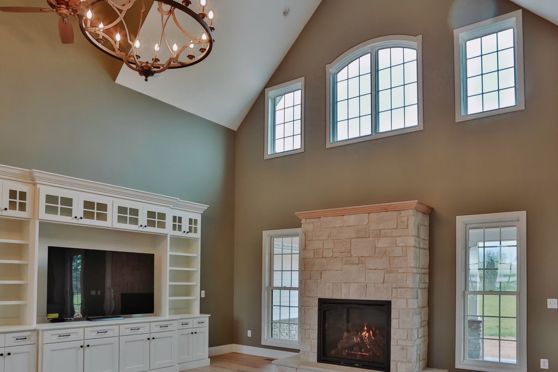 Living room with fireplace, high ceilings, built-in entertainment center, and large windows.