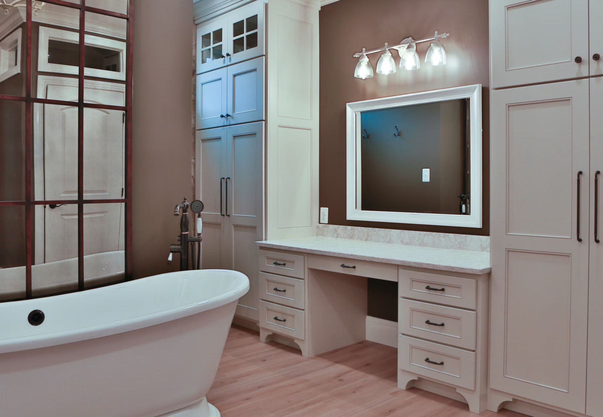 Spacious bathroom with a freestanding tub, vanity with mirror, and tall white storage cabinets.