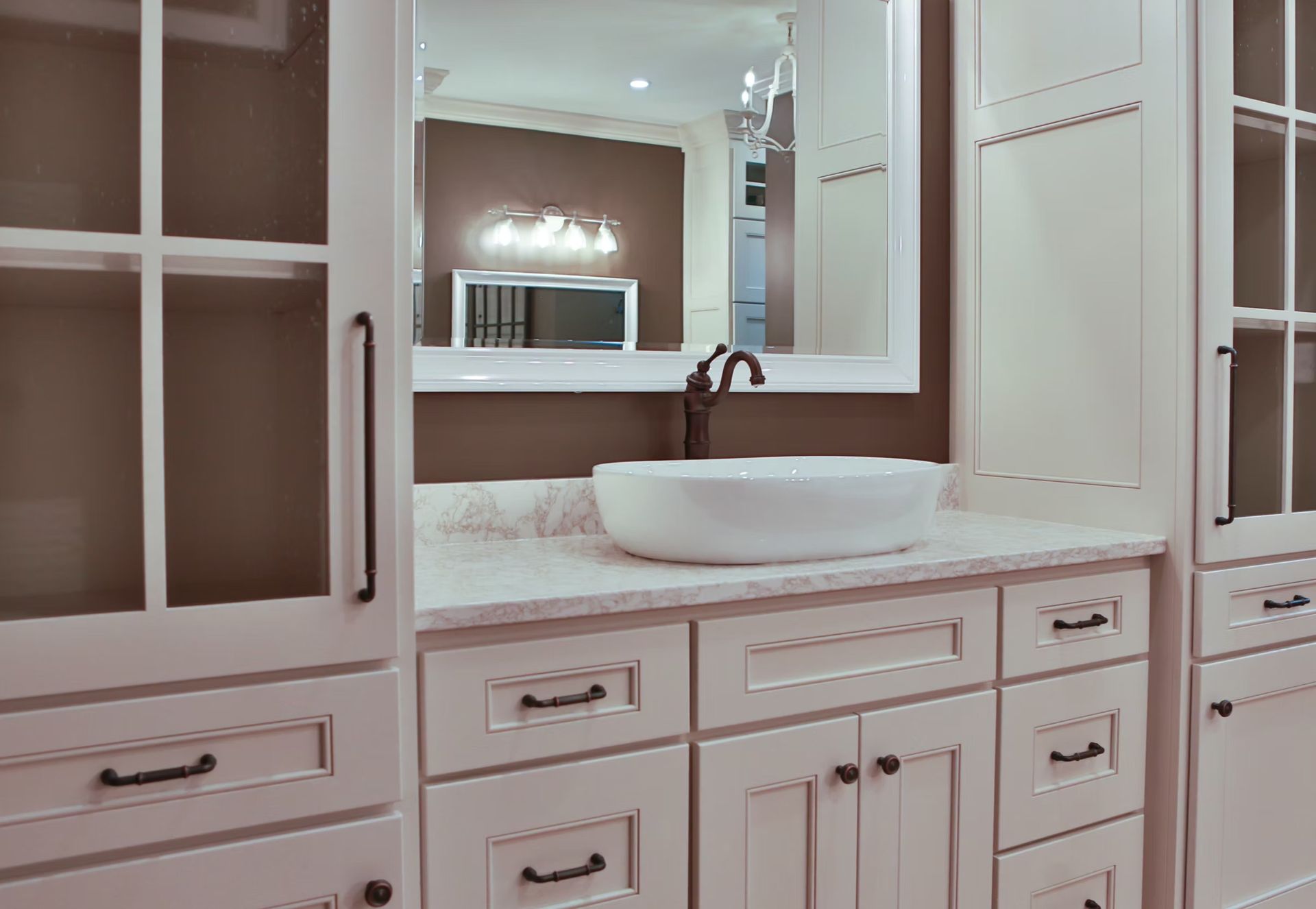Bathroom vanity with white cabinets, vessel sink, and large mirror.