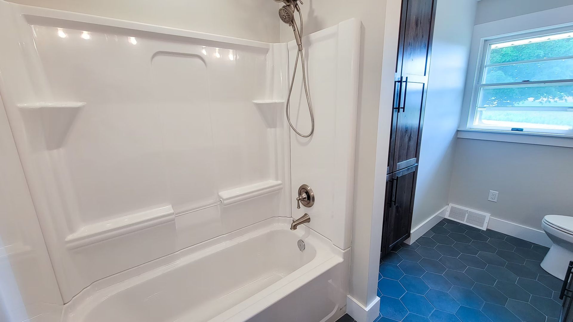 White bathroom with a shower/tub combo and a dark blue floor.