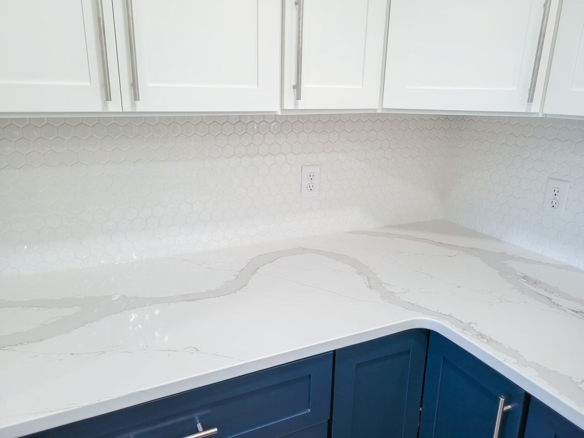 White and blue kitchen with quartz countertops and white cabinets.
