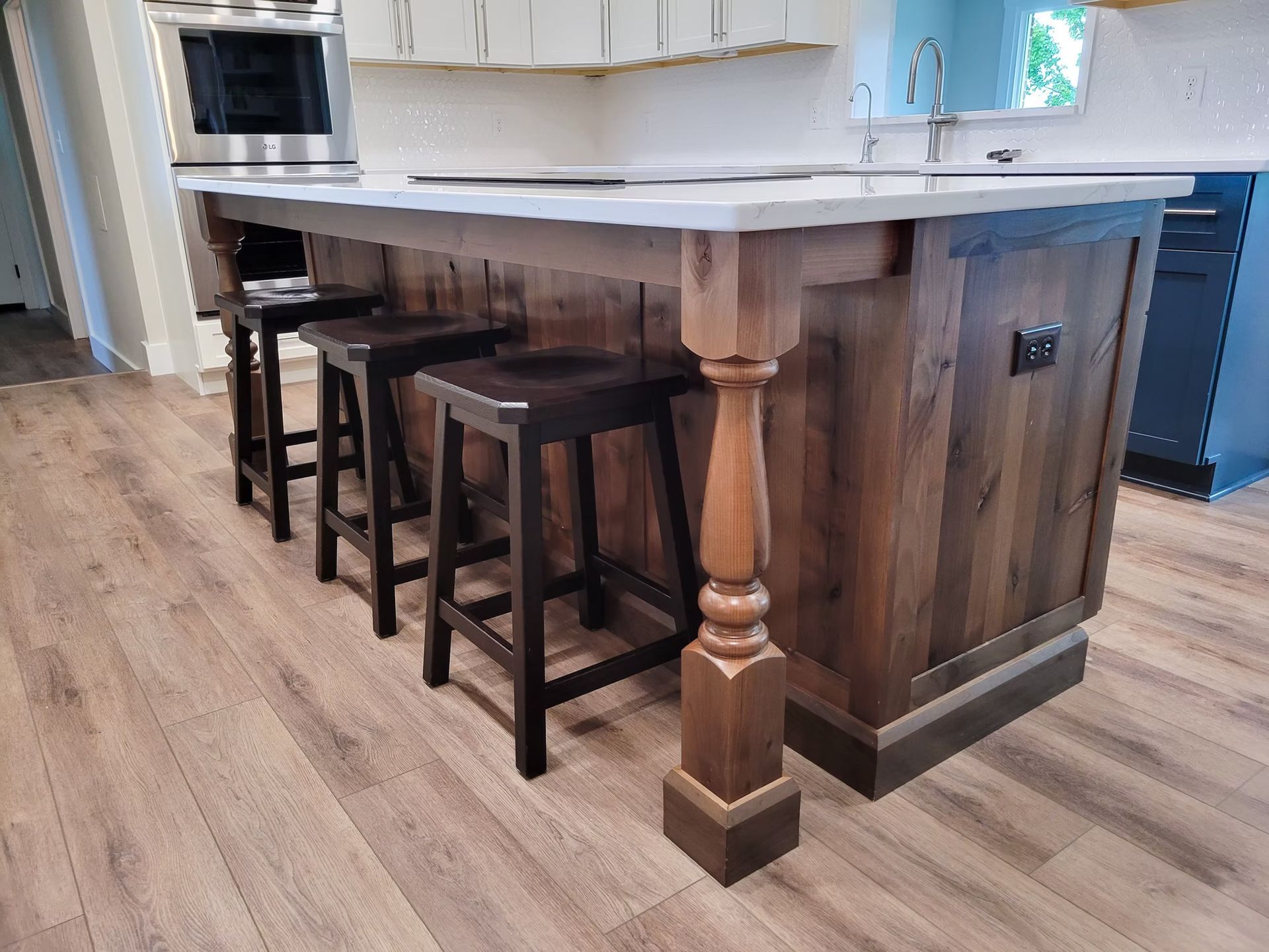 Kitchen island with wooden panels, marble countertop, bar stools, and a decorative leg.
