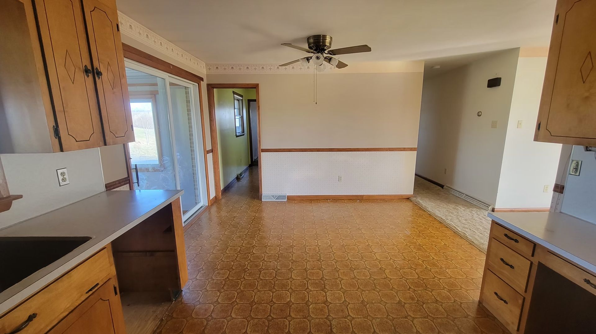 Kitchen with wood cabinets, linoleum floor, dining area, and a sliding glass door.