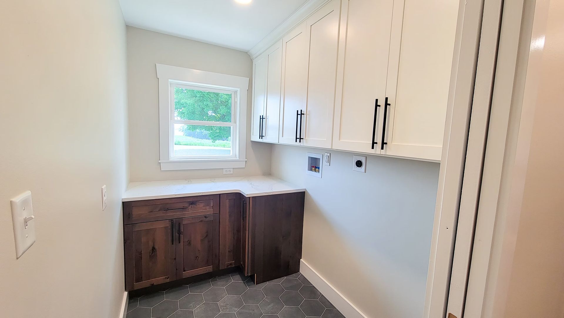 Laundry room with white upper cabinets, brown lower cabinets, and a window.