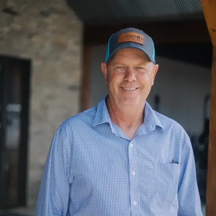 Smiling man in a blue checkered shirt and cap standing indoors