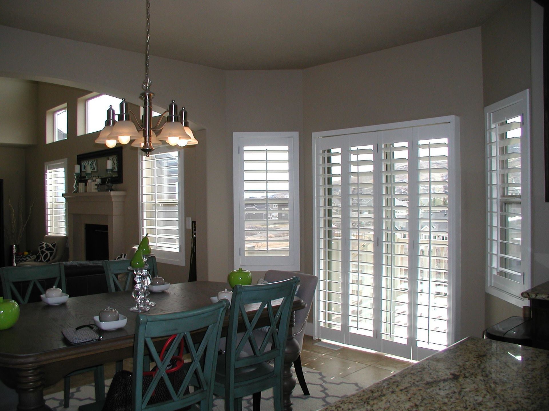 Dining room with a table and chairs, shuttered windows, and a chandelier.