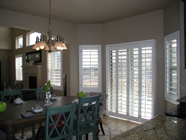 Dining room with a table and chairs, shuttered windows, and a chandelier.