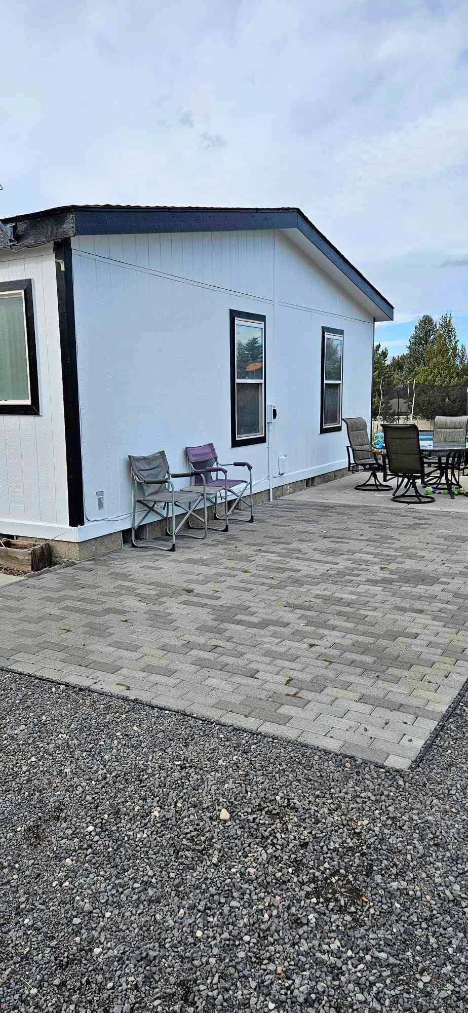 A white mobile home with a patio and chairs in front of it.