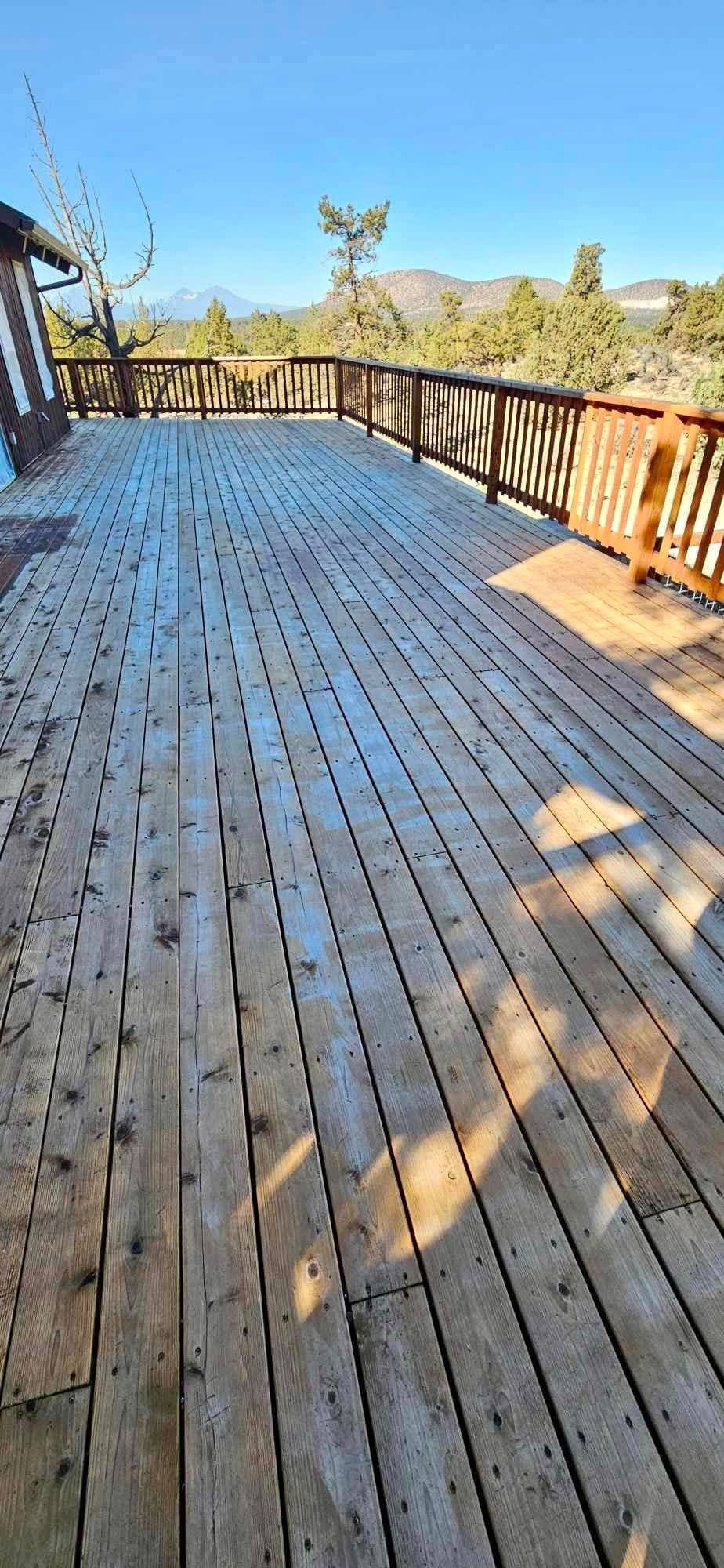 A large wooden deck with a railing on a sunny day.