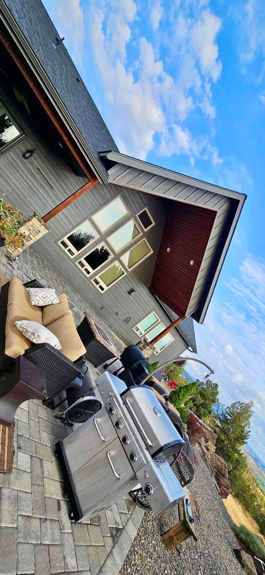 A large grill is sitting on a patio in front of a house.