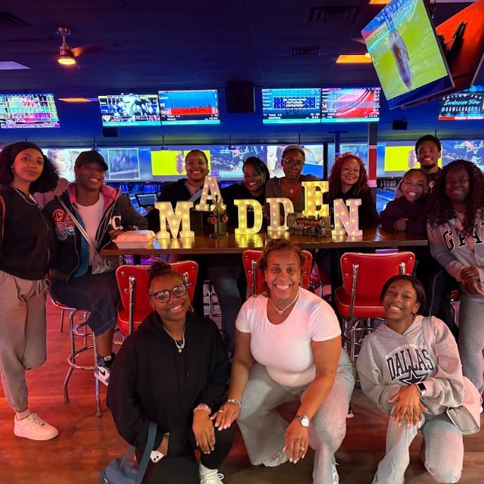 A group of people posing for a picture in front of a sign that says Madden