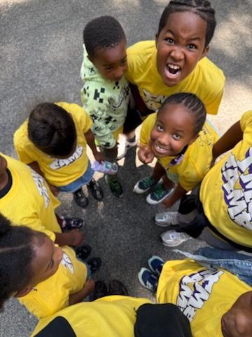 A group of children in yellow shirts are standing in a circle
