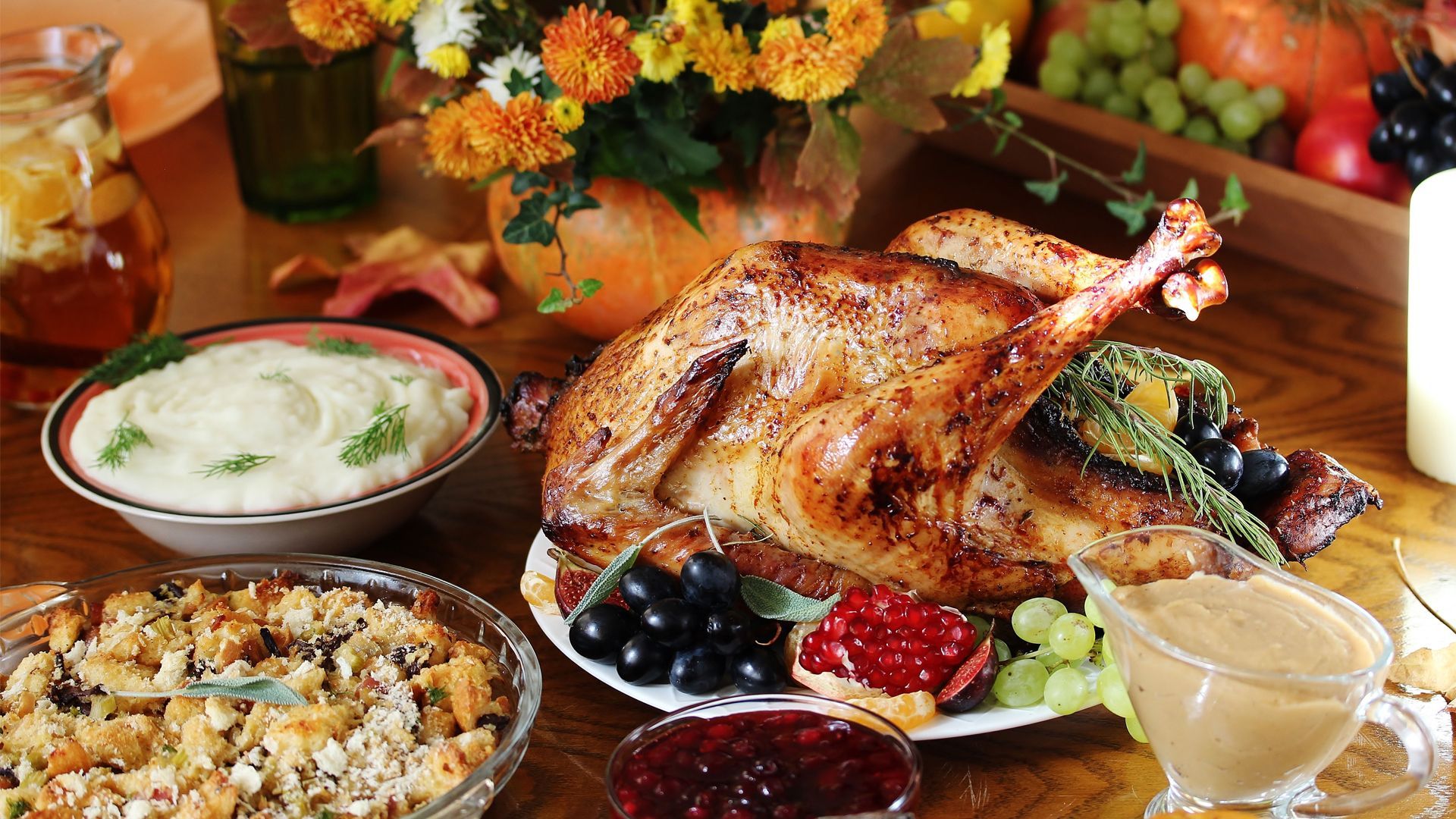 A table topped with a turkey , mashed potatoes , cranberry sauce and stuffing.