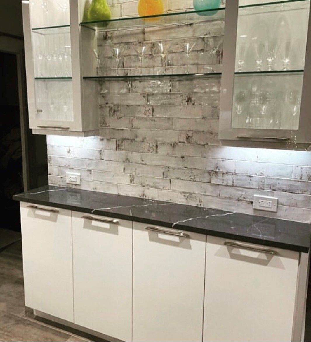 A kitchen with white cabinets and a brick wall