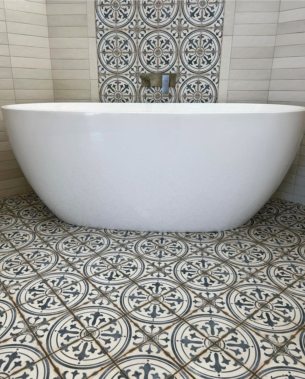 A white bathtub is sitting on a tiled floor in a bathroom