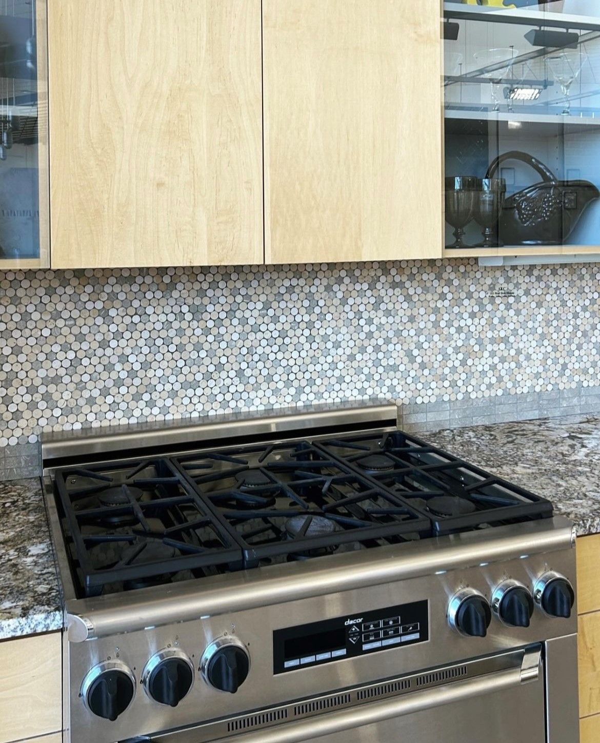 A stove top oven is sitting on a granite counter top in a kitchen